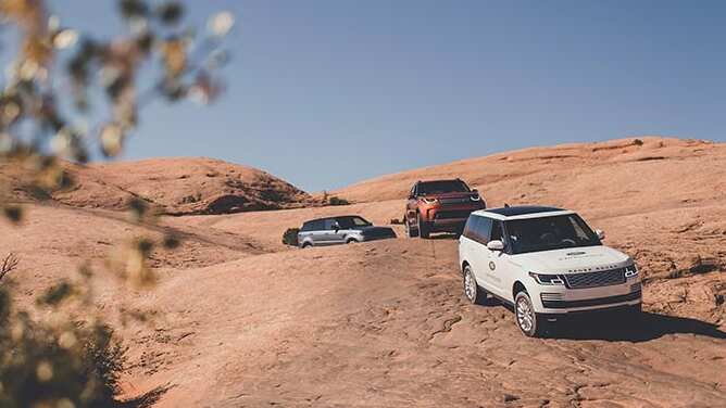 Three range rovers driving in rock scenery