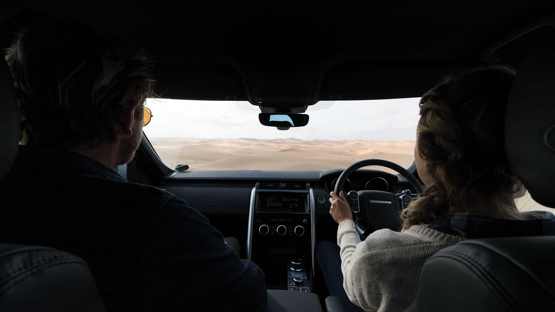 Two people driving through a desert