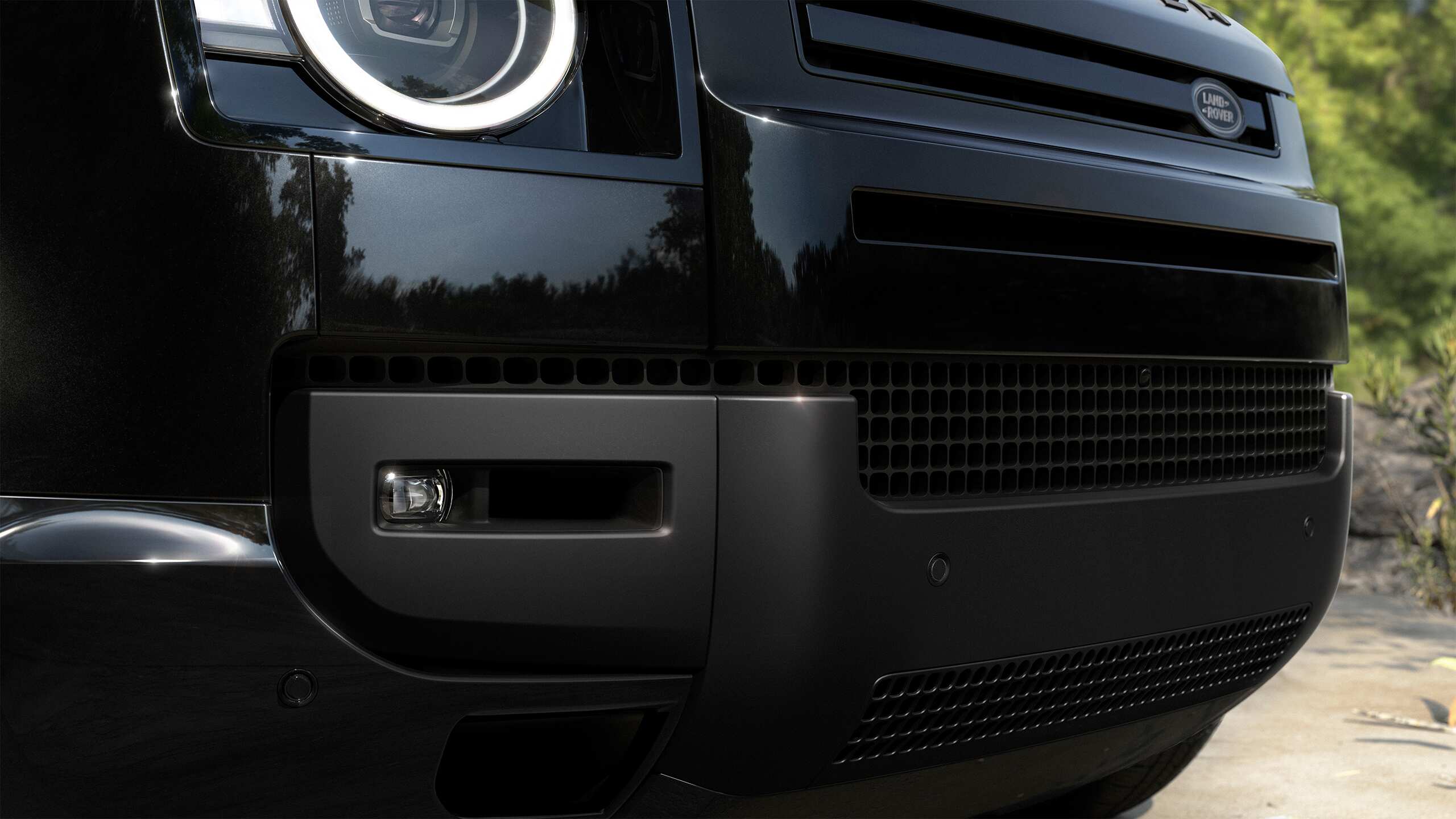 Close-up of the front bumper and headlight of a black Defender.